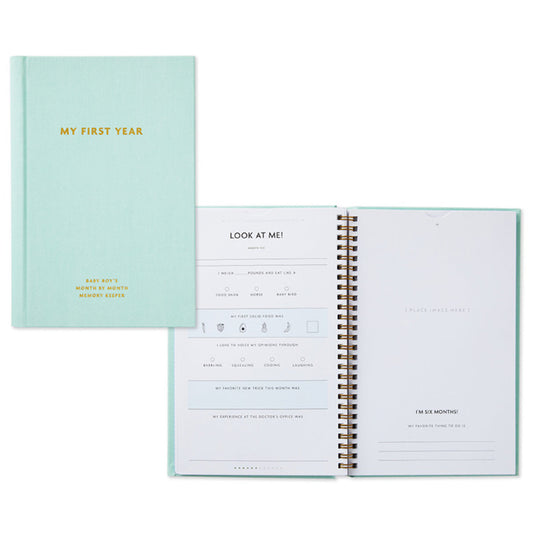 My First Year Baby Book - Blue, fabric-wrapped hardcover, opened pages showing journal prompts and memento sections.