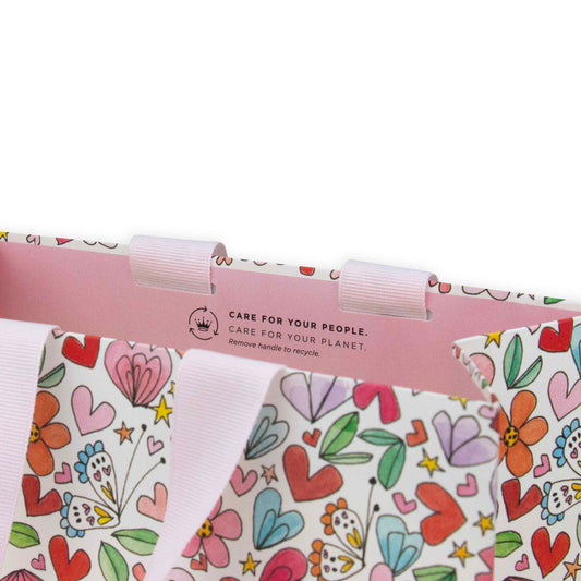 Hallmark x Love, Meredith Medium Gift Bag - Butterflies, Hearts, Stars & Flowers featuring pink grosgrain handles and colourful floral pattern.
