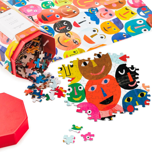 Share Smiles 550-piece jigsaw puzzle (45.8cm x 61cm) with colourful faces, pieces spilling from hexagon box.