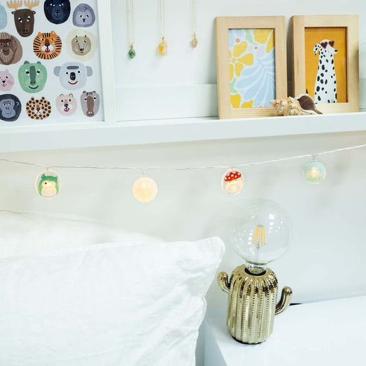 Squishmallows 2D String Lights featuring cute animal designs on a warm string, displayed above a white cushion in a contemporary bedroom setting.