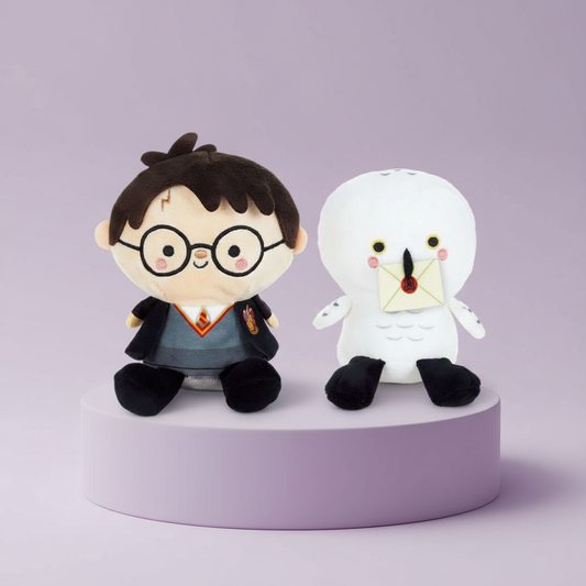 Harry Potter Hedwig, Two plush toys, one resembling harry potter character with glasses and a robe, and the other resembling a hedwig owl, on a purple platform.