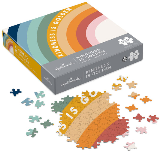 Kindness Is Golden 550-Piece jigsaw puzzle box with colourful rainbow design and scattered puzzle pieces in various shades.