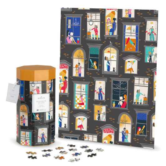 Snapshots of Life 1,000 piece jigsaw puzzle including a cylindrical box and an illustrated image of apartment windows, flat lay view.