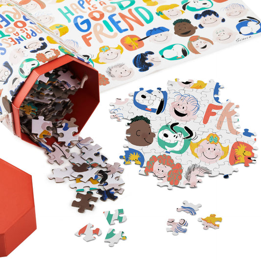 Peanuts® Gang Happiness Is 550 Piece Jigsaw Puzzle in red packaging with colourful puzzle pieces spilled out and characters visible.
