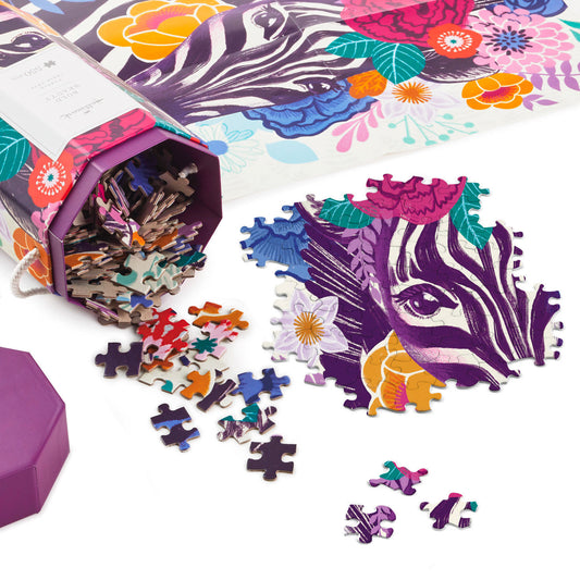 Bold Beauty 550-Piece Jigsaw Puzzle (45.7cm x 61cm) showing vibrant zebra artwork with colourful flower blossoms and scattered puzzle pieces.