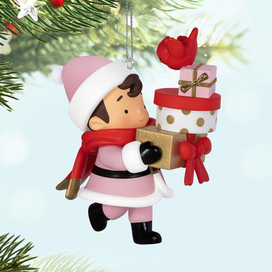2025 Young Santa Surprise Box — 2025 Hallmark Keepsake Christmas Ornament featuring a young Santa in pink holding gift boxes and a red bird, close up.
