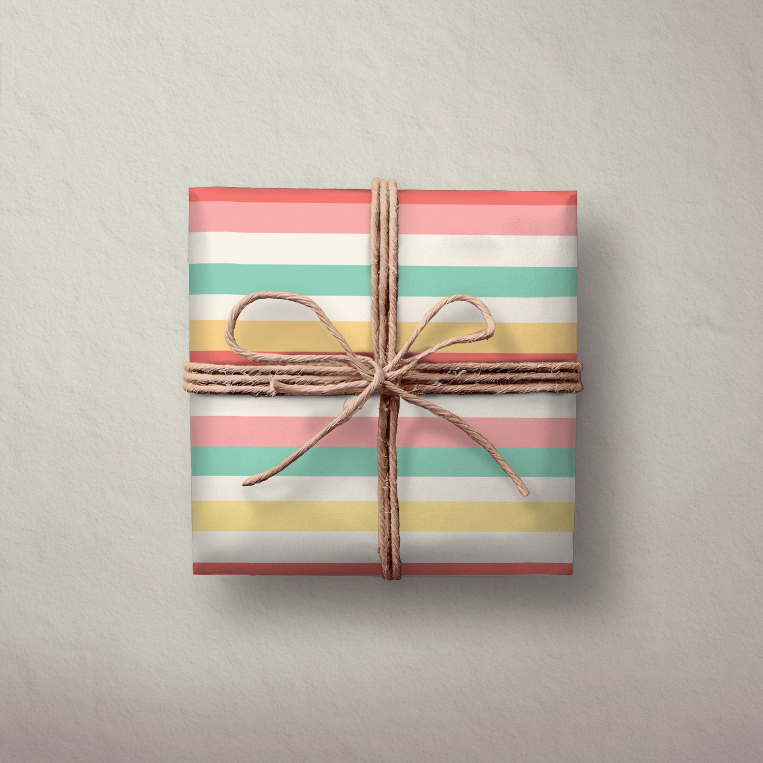 Hallmark Flat Wrapping Paper - Pastel Stripes used to wrap a gift, featuring pastel pink, yellow, green, and white stripes with twine.