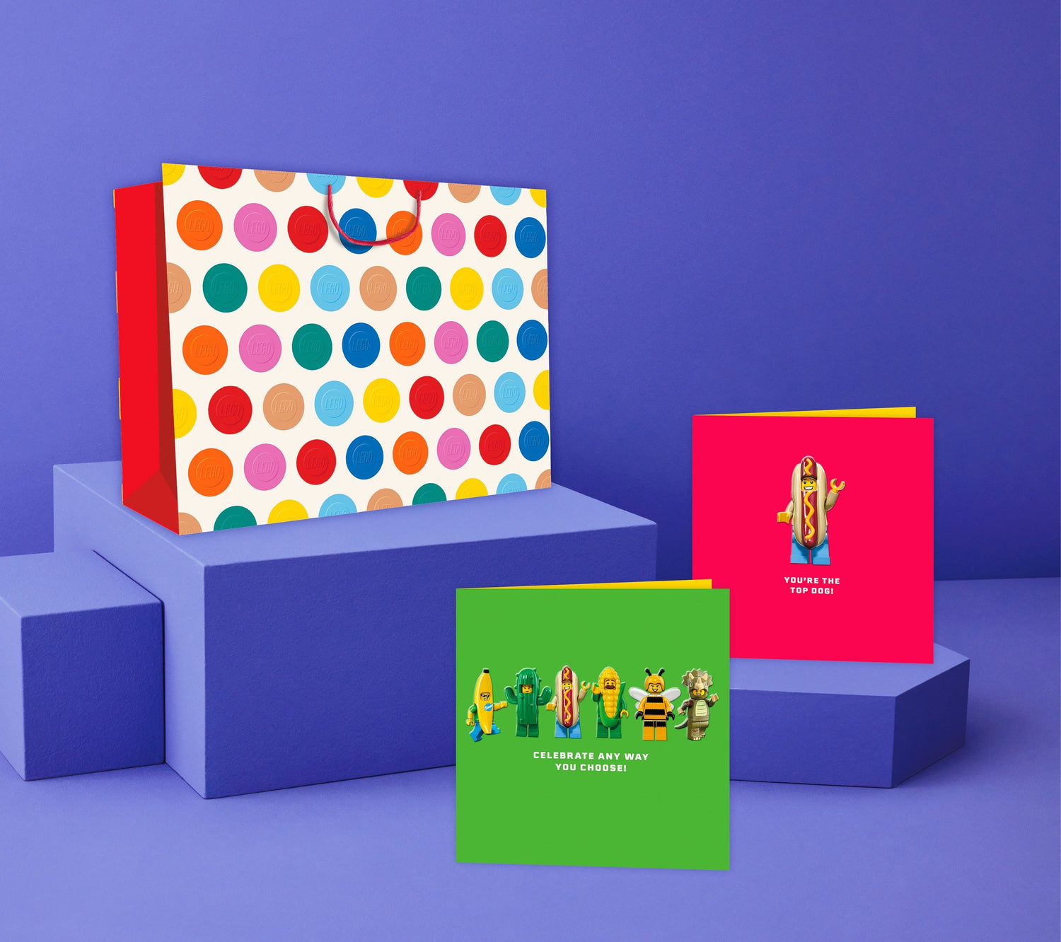 Lego greeting cards and gift bag with colourful polka dots, arranged on purple blocks for a cheerful display.