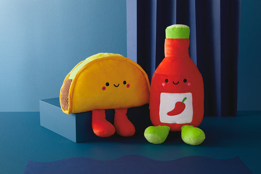 Taco and hot sauce magnetic plush (Extra Large) – Better Together, featuring bright colours, sitting on a blue surface.