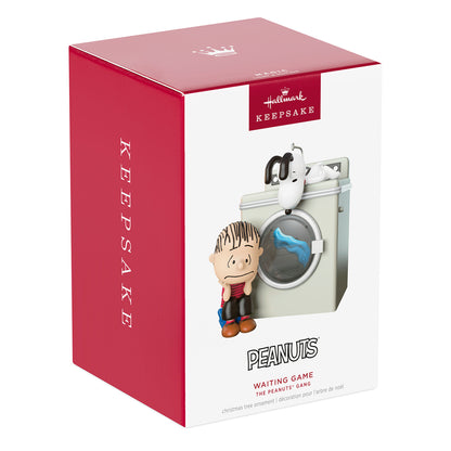 The Peanuts Gang Waiting Game With Light and Motion — 2026 Hallmark Keepsake Christmas Ornament packaging featuring Linus by a washing machine.