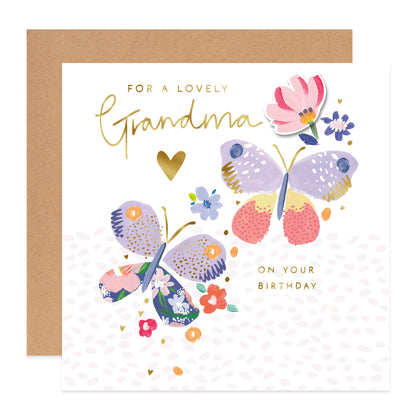 A square greeting card with a kraft envelope behind it. The card reads 'FOR A LOVELY Grandma ON YOUR BIRTHDAY' in gold lettering, with two illustrated butterflies and small flowers in pastel colors on a white background.