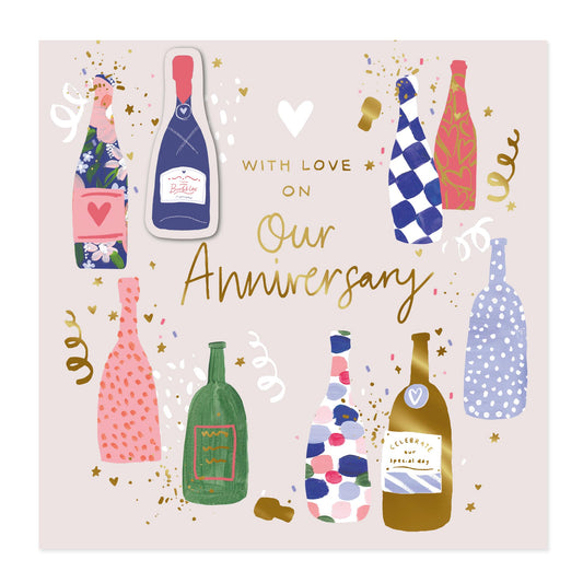 A square anniversary card design with the text 'WITH LOVE ON Our Anniversary' in gold and white lettering. The background is a soft blush pink, decorated with eight whimsical champagne bottles in various colorful patterns (checkered, polka dot, floral, solid green, and gold) along with small gold confetti and streamers.