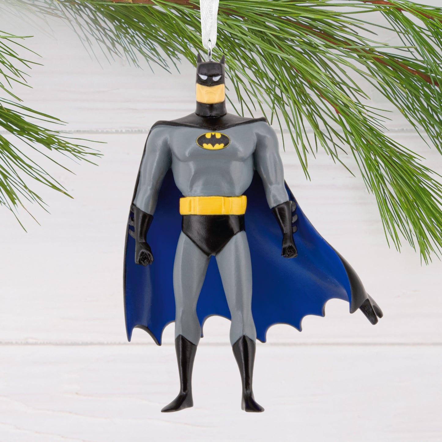 Resin Figural Batman ornament featuring a detailed design and vibrant colours, hanging from a pine branch.