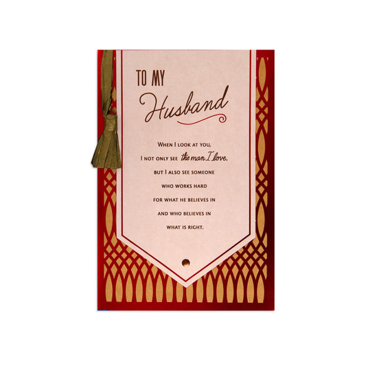 A rectangular greeting card or gift tag with a red border and ornate gold pattern, featuring a cream center panel that reads 'TO MY Husband' and a sentimental message. A small olive-brown tassel hangs from the left side.