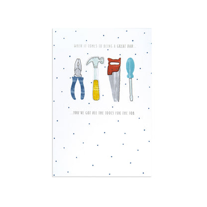 A white greeting card with a dotted pattern and an illustration of four hand tools—a pliers, hammer, saw, and screwdriver—centered on the front. Small printed text appears above and below the tool illustration.