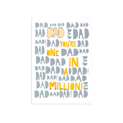 A vertical greeting card featuring the phrase 'Dad You're One in a Million!' in yellow text, with 'Dad' repeated in light gray and a small pale yellow bow tie graphic, shown on a white background.