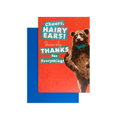 A greeting card with a bright red front featuring a brown bear wearing a blue bow tie and retro text reading 'Cheers, Hairy Ears! Seriously Thanks for Everything!', shown with a blue envelope behind it on a white background.