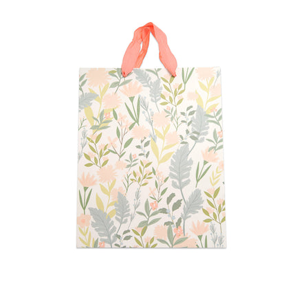 A square gift bag with a delicate botanical pattern of pink flowers and green leaves on a cream background, featuring two coral-pink ribbon handles, shown against a plain white background.