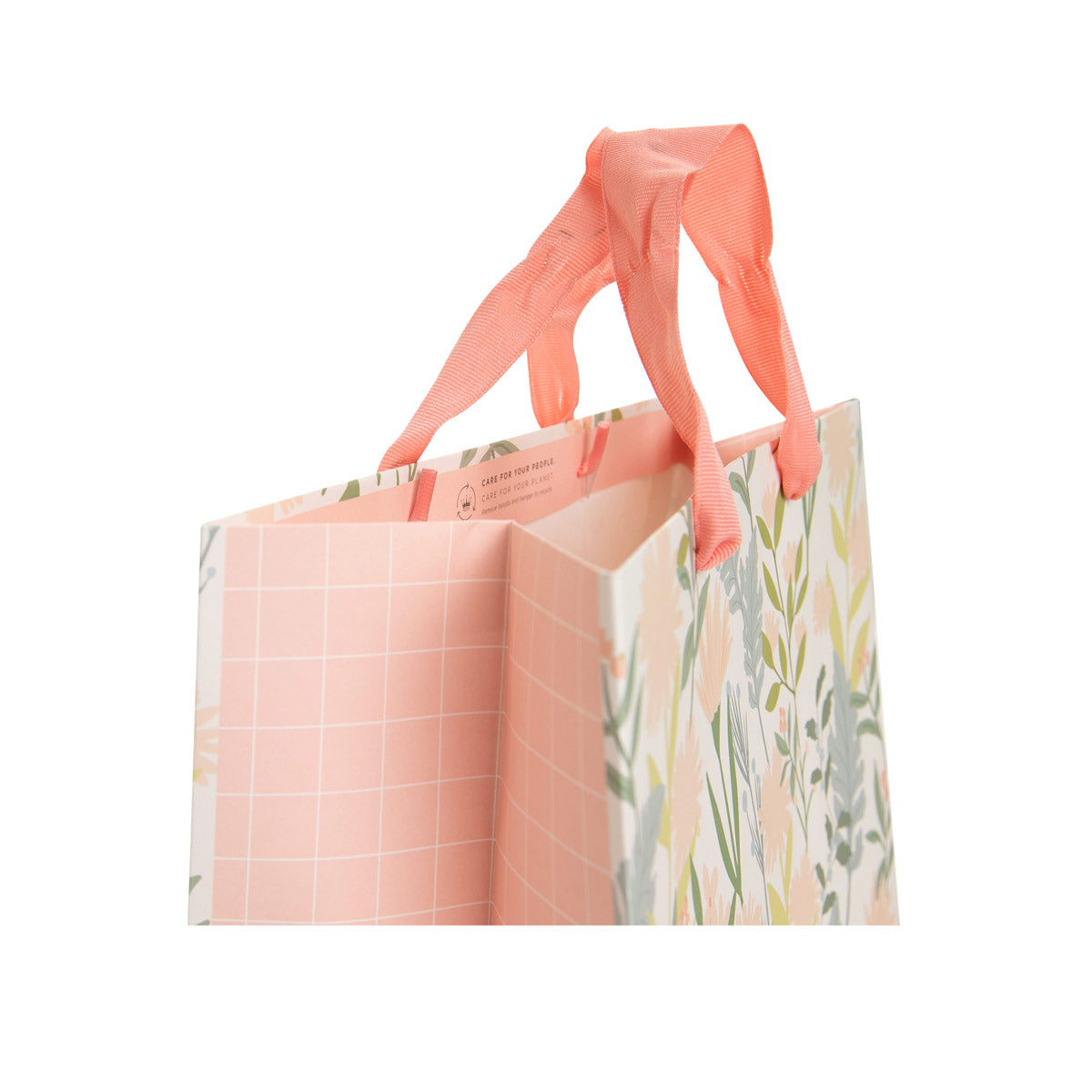 A reusable paper shopping bag with coral pink fabric handles, featuring a pink grid pattern on one side and a pastel floral print on the other, shown on a solid white background.