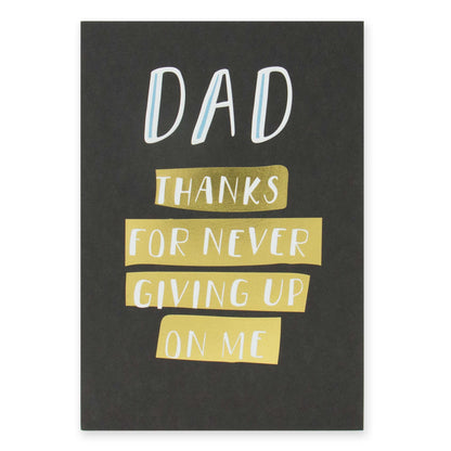 Hallmark Father's Day card - Thanks For Never Giving Up On Me, features gold foil highlights on a black background, flat lay view.