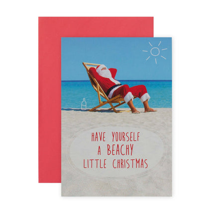 Hallmark Christmas Card - Beachy Christmas features Santa lounging on a beach chair by the ocean with a bright blue sky.