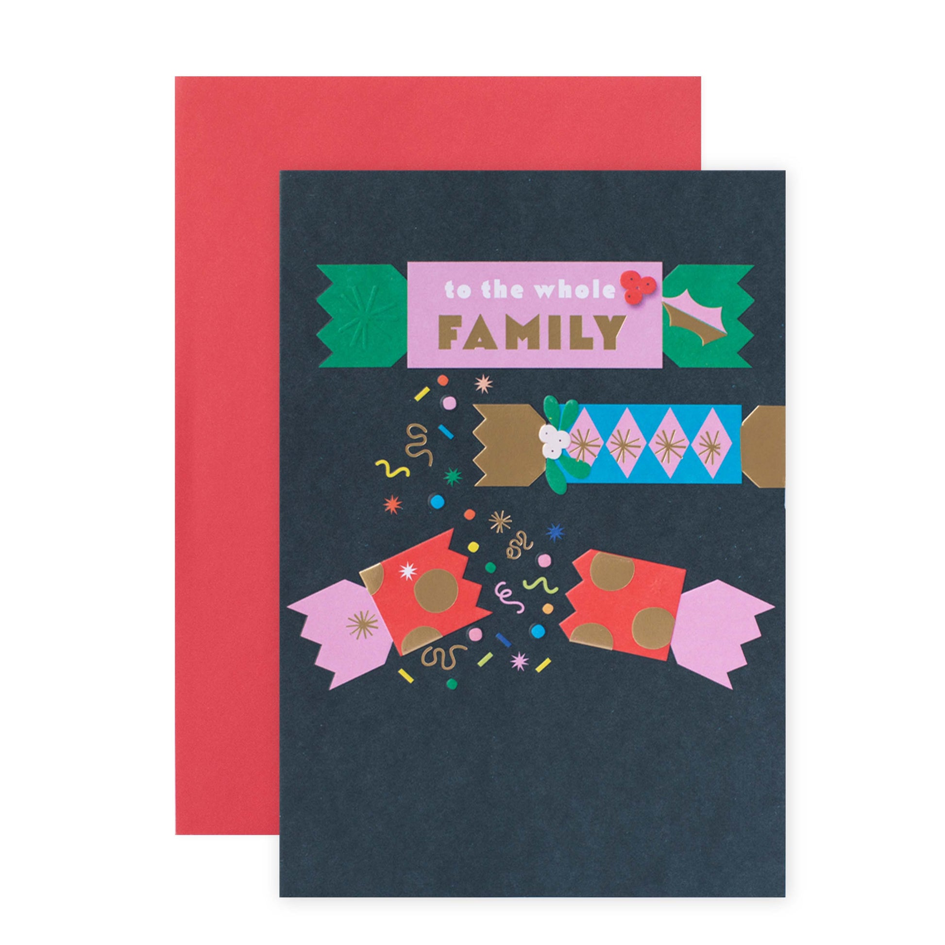 A dark navy greeting card with a colorful Christmas-themed illustration and the words 'to the whole FAMILY' in a pink banner, shown with a red envelope behind it on a white background.