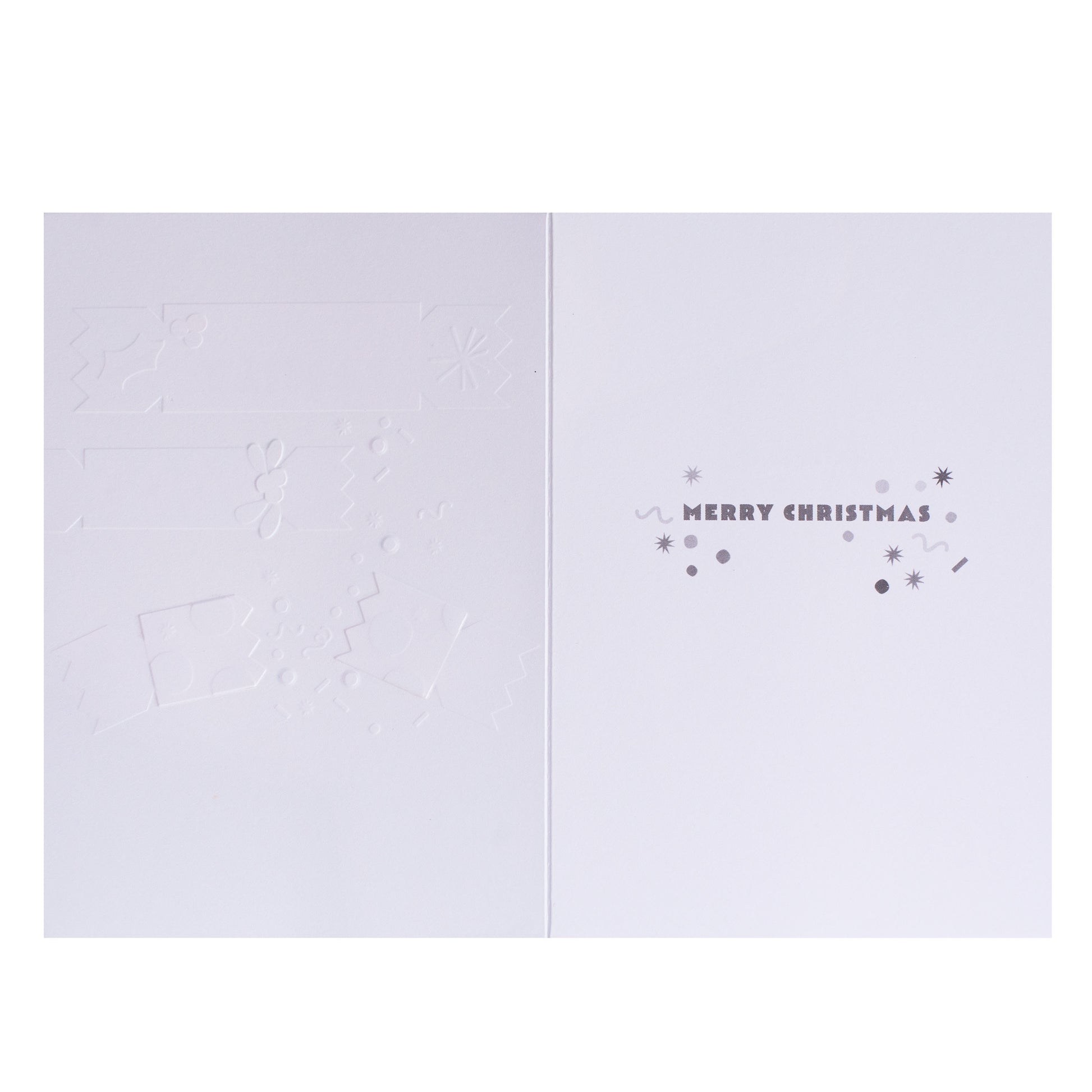 A minimalist white Christmas greeting card shown open, with embossed holiday motifs on the left panel and the right panel reading “MERRY CHRISTMAS” in small gray lettering with decorative dots and stars.