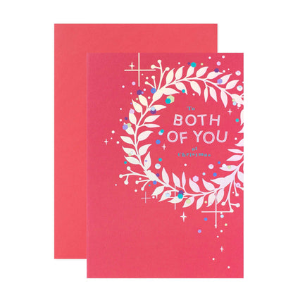 Hallmark Christmas Card For Both Of You - With Love featuring a pink front with a wreath illustration and festive accents, flat lay view.