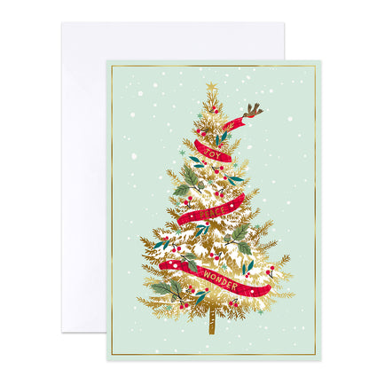 A Christmas greeting card with a mint green background, featuring a decorated gold pine tree with red ribbons, white snow, and green leaves. A white envelope is placed behind the card.
