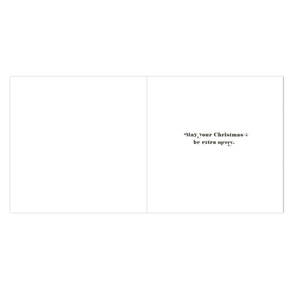 A blank greeting card shown open against a white background, with small black text on the right side reading, "May your Christmas be extra merry.".