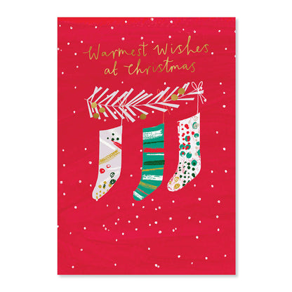 Hallmark Christmas Card - Warmest Wishes features three decorated stockings hanging from a garland on a vibrant red background.