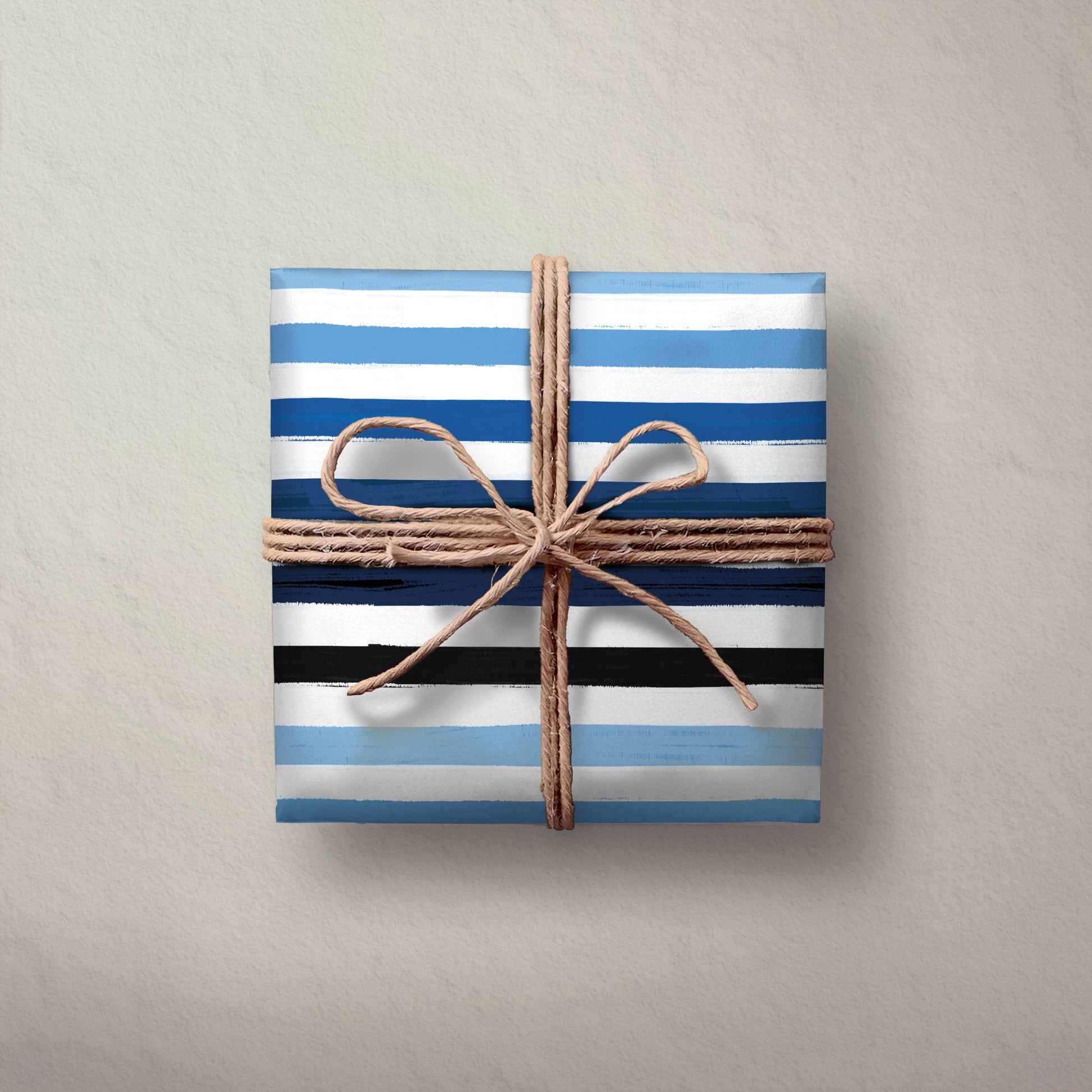 Hallmark Flat Wrapping Paper - Blue Brushstrokes gift wrapped box in blue and black stripes, tied with natural twine on a textured background.