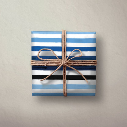 Hallmark Flat Wrapping Paper - Blue Brushstrokes gift wrapped box in blue and black stripes, tied with natural twine on a textured background.