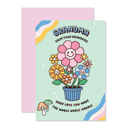 Hallmark Mother's Day Card For Grandma - From Grandkids featuring cheerful illustration of smiling flowers and mushrooms, flat lay view with pink envelope.