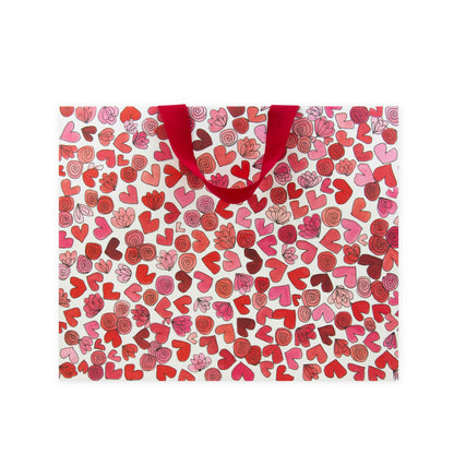 Hallmark x Love, Meredith Large Gift Bag - Hearts & Flowers featuring a vibrant pattern of red and pink hearts with a red grosgrain ribbon handle.