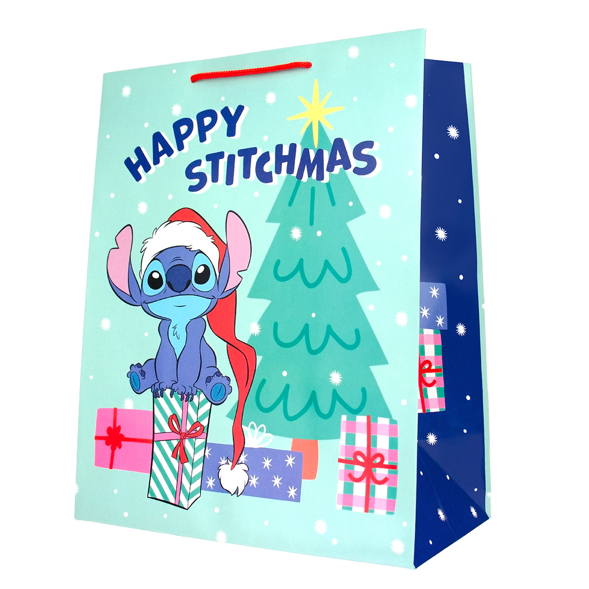 A festive paper gift bag featuring Stitch from Disney's Lilo & Stitch on a light blue holiday background with the text 'Happy Stitchmas,' a green Christmas tree, wrapped presents, and a dark blue side panel with white snowflakes.
