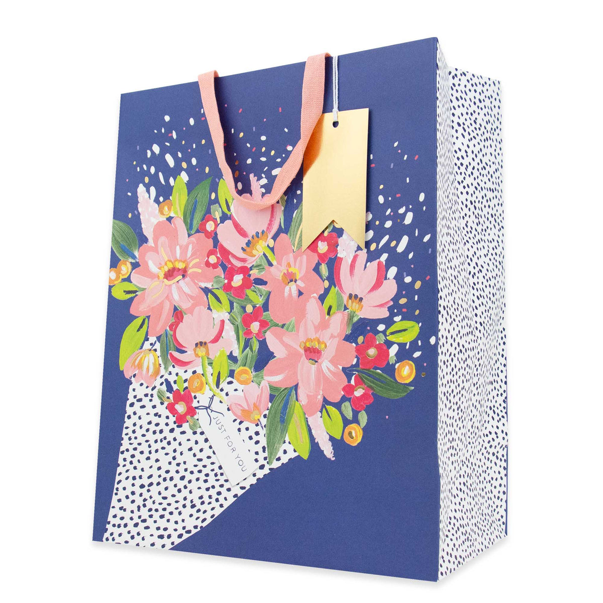 A navy blue gift bag with a floral bouquet illustration on the front, pink paper handles, a gold hang tag, and a white side panel with black polka dots, shown on a clean white background.