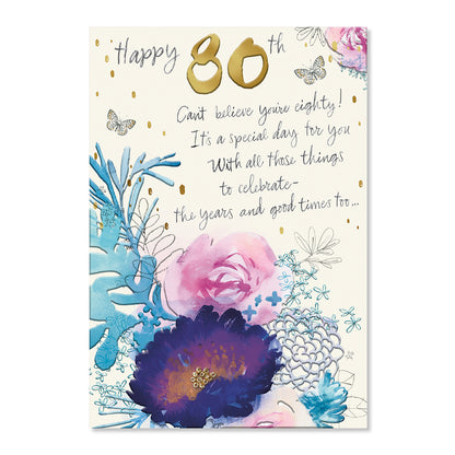 An 80th birthday greeting card with a cream background, featuring the text 'Happy 80th' in gold and black script, a celebratory message, and watercolor-style floral illustrations in pink, purple, and blue with gold confetti accents.