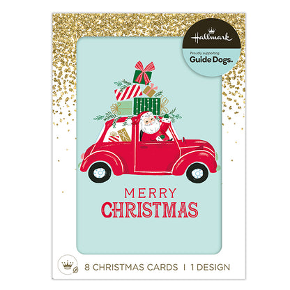 Hallmark Christmas cards featuring a festive illustration of Santa Claus driving a red car loaded with gifts, with 'MERRY CHRISTMAS' text below, shown in its retail packaging with gold glitter borders.