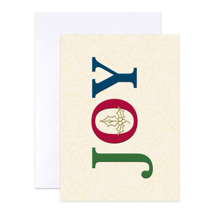 A vertical Christmas greeting card with the word 'JOY' spelled out in large letters. The 'J' is blue, the 'O' is a red oval with a gold holly leaf design inside, and the 'Y' is green.