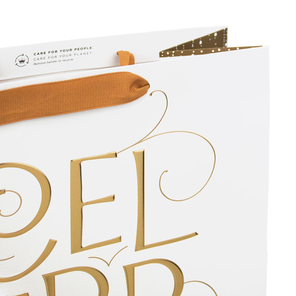 A close-up of a white gift bag with metallic gold typography and a rust-orange ribbon handle, photographed on a clean white background.
