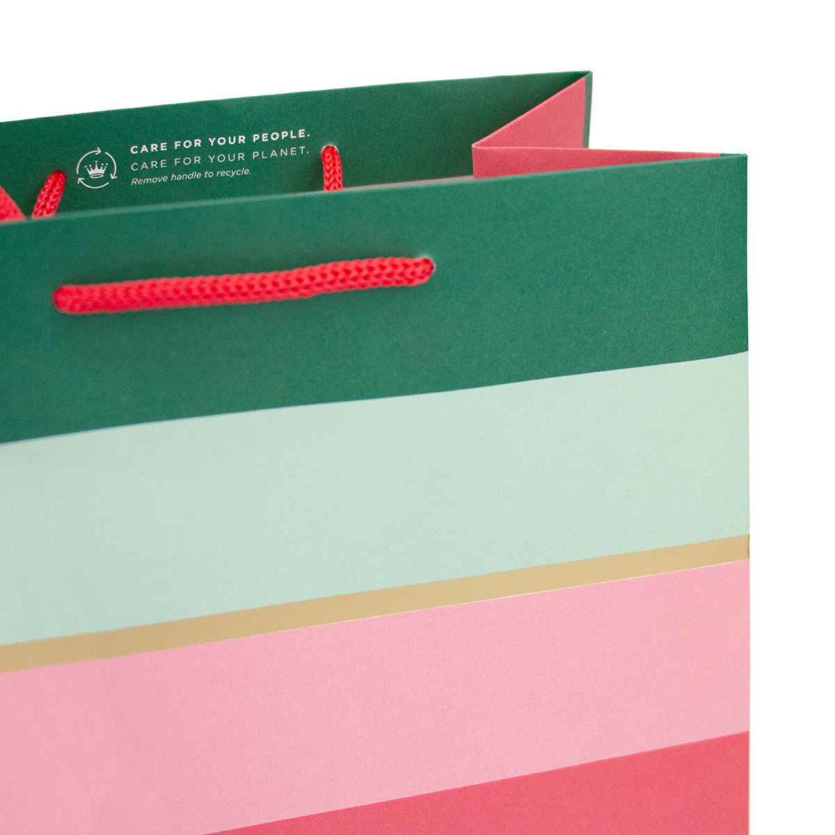 A close-up of a paper shopping bag with a dark green top section, red rope handles, and broad horizontal stripes in pale mint green, white, pink, and coral red on a white background.