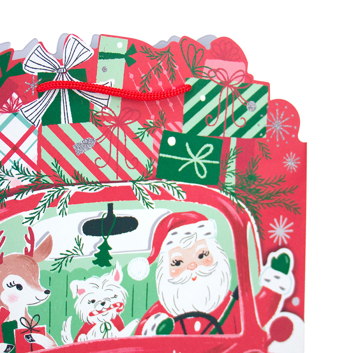 A close-up of a festive Christmas gift card or paper decoration featuring Santa Claus in a red truck, with a deer, a white dog, wrapped presents, pine branches, snowflakes, and red ribbon bows on a white background.