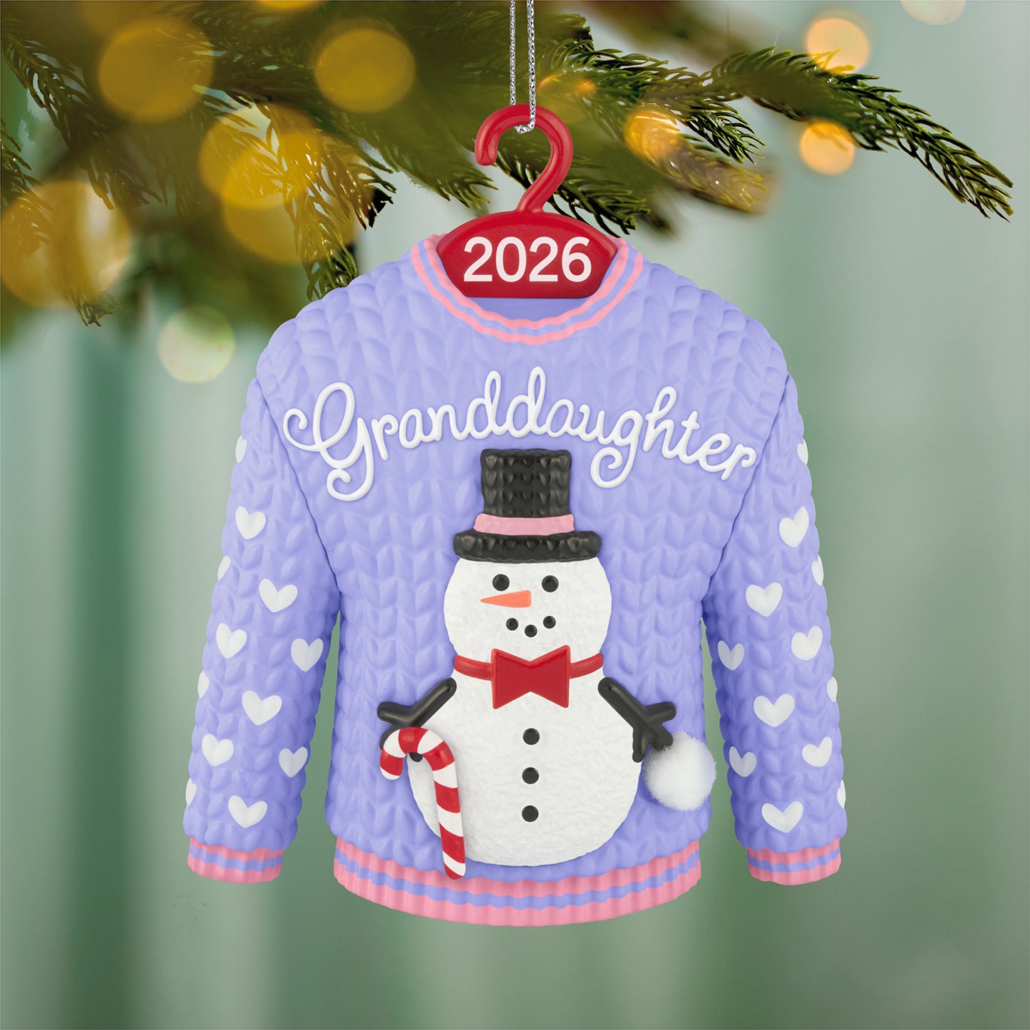 Granddaughter Snowman Sweater 2026 — 2026 Hallmark Keepsake Christmas Ornament, purple and pink design featuring a snowman and hearts, hanging on a tree.