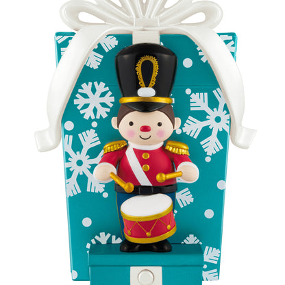 Toy soldier musical with motion — 2026 Hallmark Keepsake Christmas ornament, colourful design, standing in front of a large wrapped present with snowflakes.