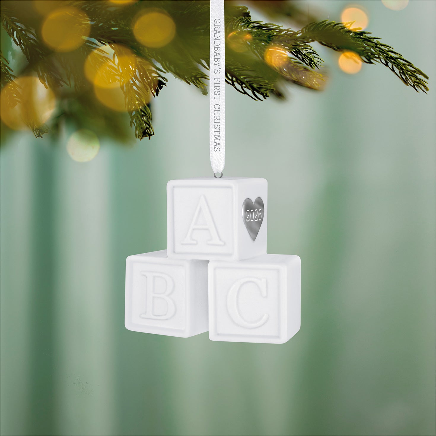 Grandbaby's First Christmas Blocks 2026, porcelain Christmas ornament featuring white toy blocks with silver heart detail, hanging on a tree.