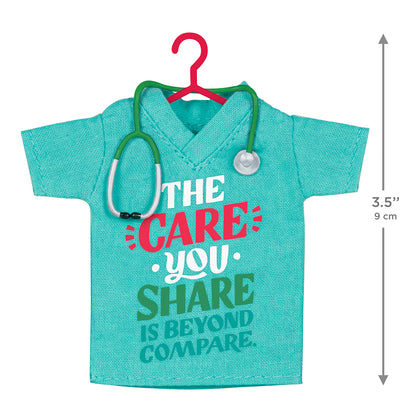 The Care You Share, Fabric — 2026 Hallmark Keepsake Christmas Ornament featuring a teal scrubs shirt with stethoscope detail in flat lay view.