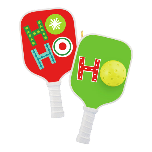 Merry Pickleball — 2026 Hallmark Keepsake Christmas Ornament, colourful pickleball paddles with textured handles and a yellow ball, flat lay view.