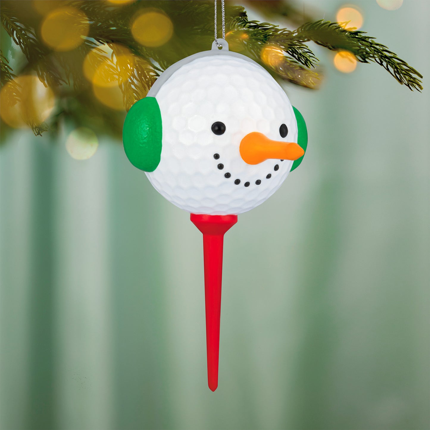 Teed Up for Christmas — 2026 Hallmark Keepsake Christmas Ornament, white golf ball snowman with green ears and red tee, hanging on tree.