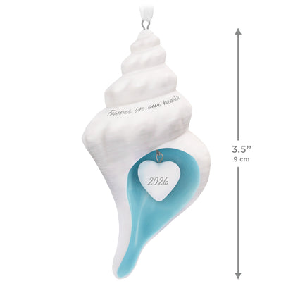 Forever in our hearts shell 2026, porcelain ornament with blue interior and heart charm, hanging view, 9 cm
